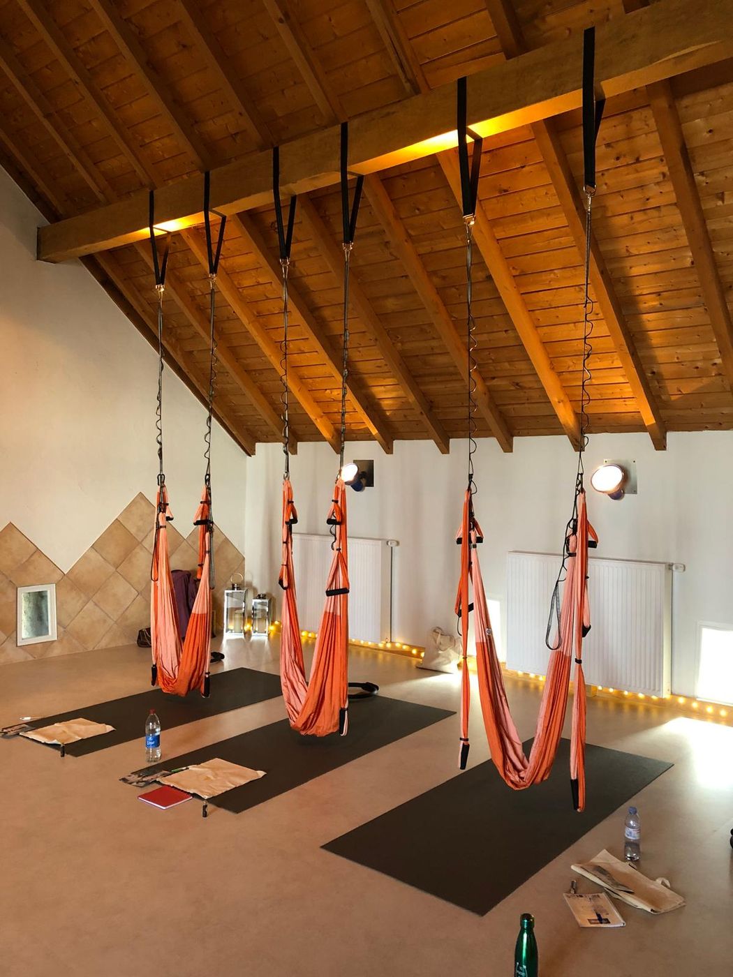 Sala de formação com tecidos laranja suspensos, tapetes e cadernos
