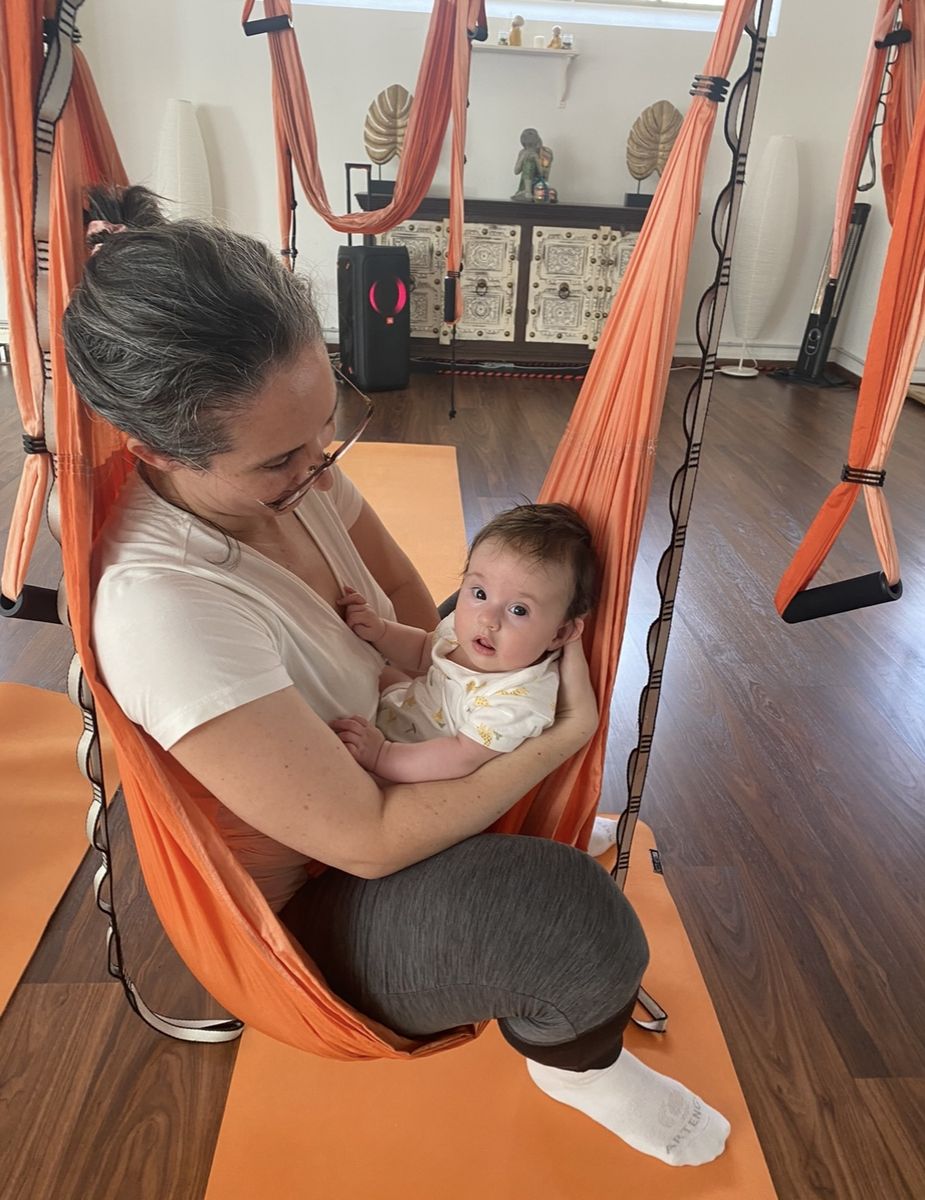 Mãe sentada no tecido laranja com o seu bebé ao colo