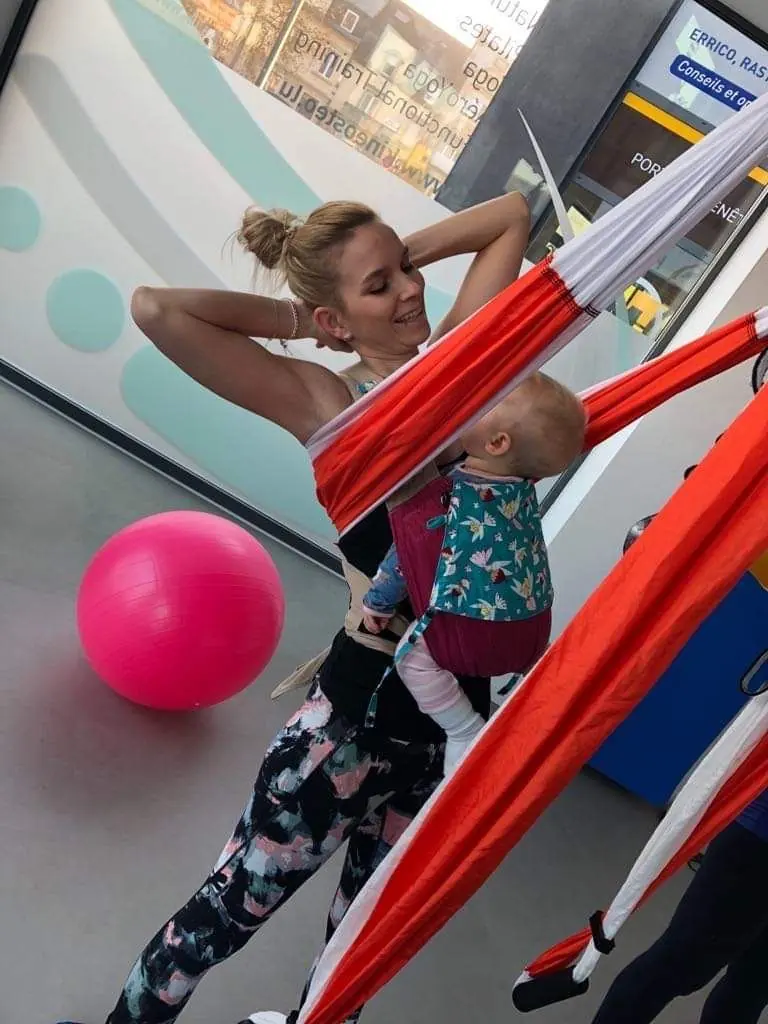 Mutter dehnt sich neben dem Tuch, ihr Baby in der Trage