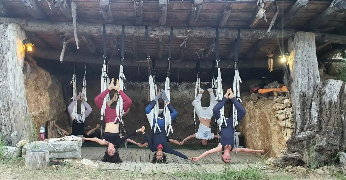 Gruppe in Umkehrhaltung in den Tüchern unter einem Holzdach, Hand in Hand