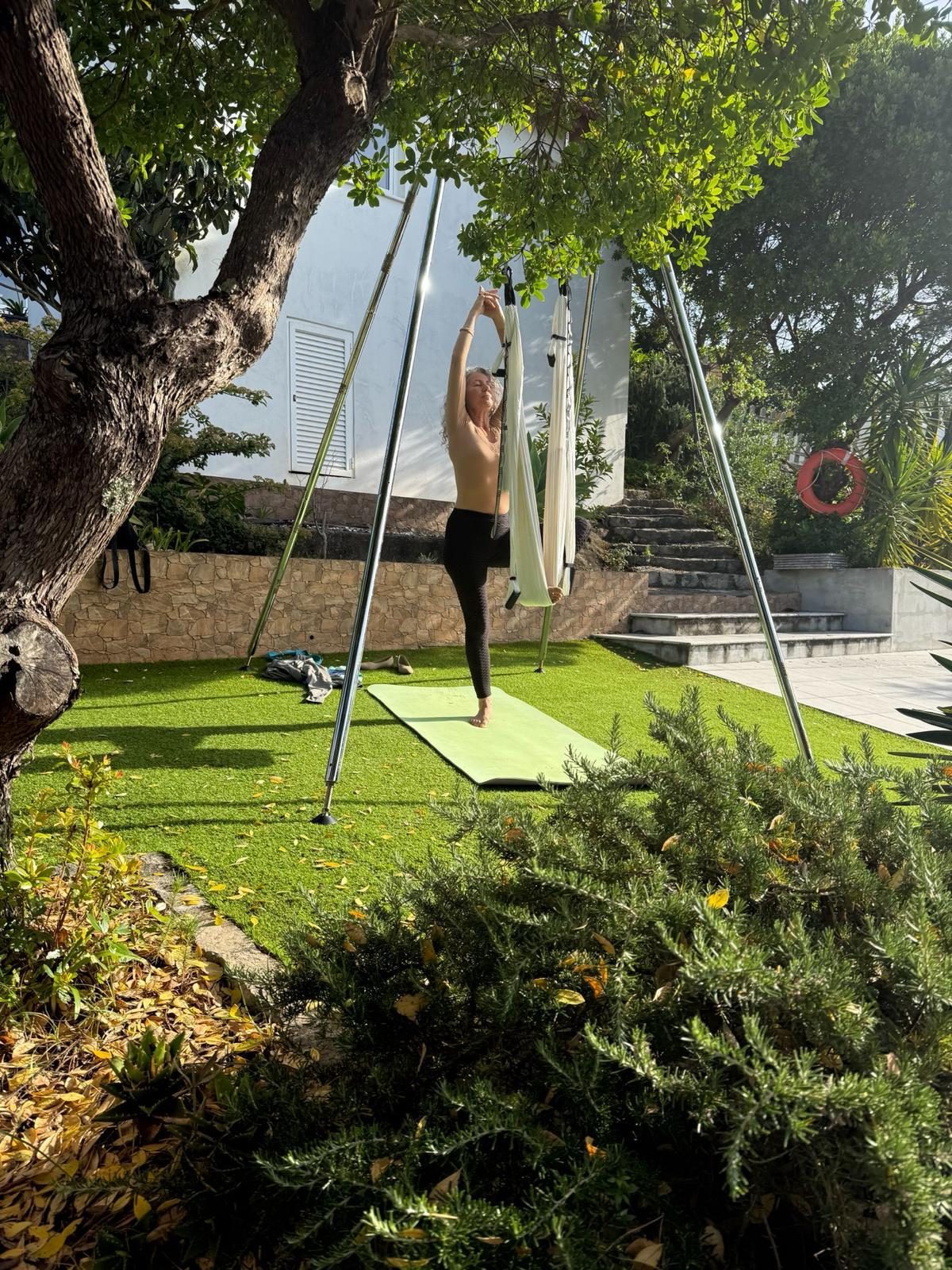 Praticante em equilíbrio junto ao tecido, num jardim ao sol