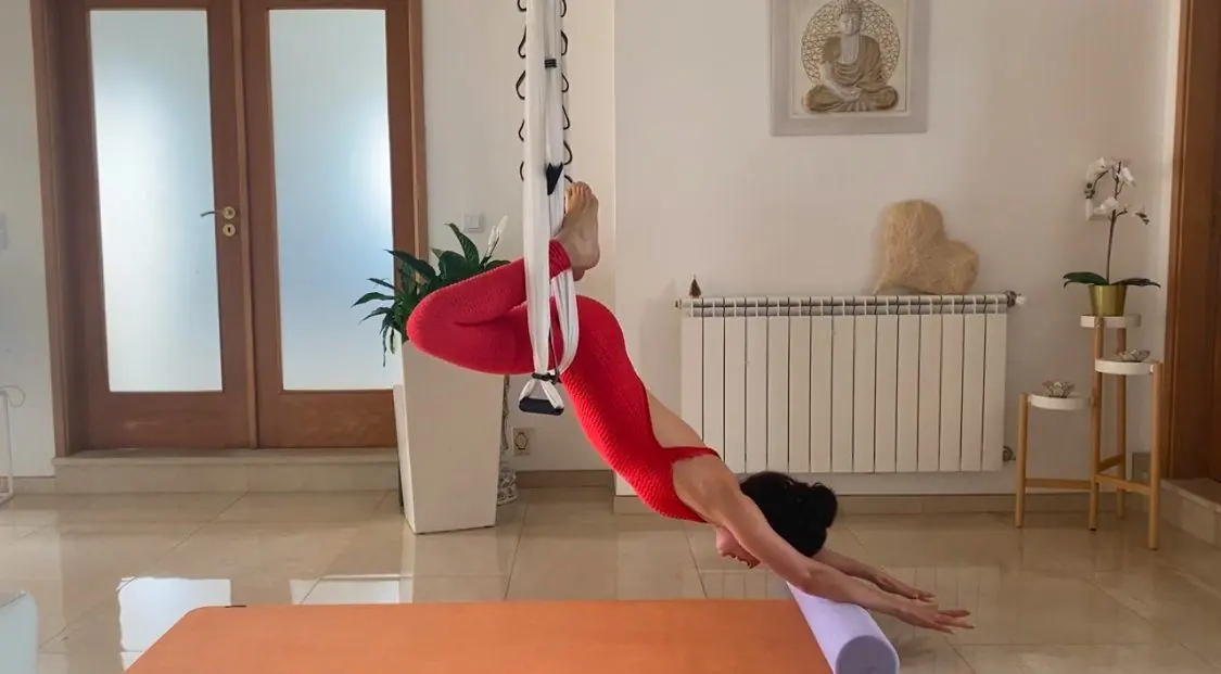 Aerial Yoga zu Hause, das Tuch an der Decke befestigt, eine Rolle auf der Matte