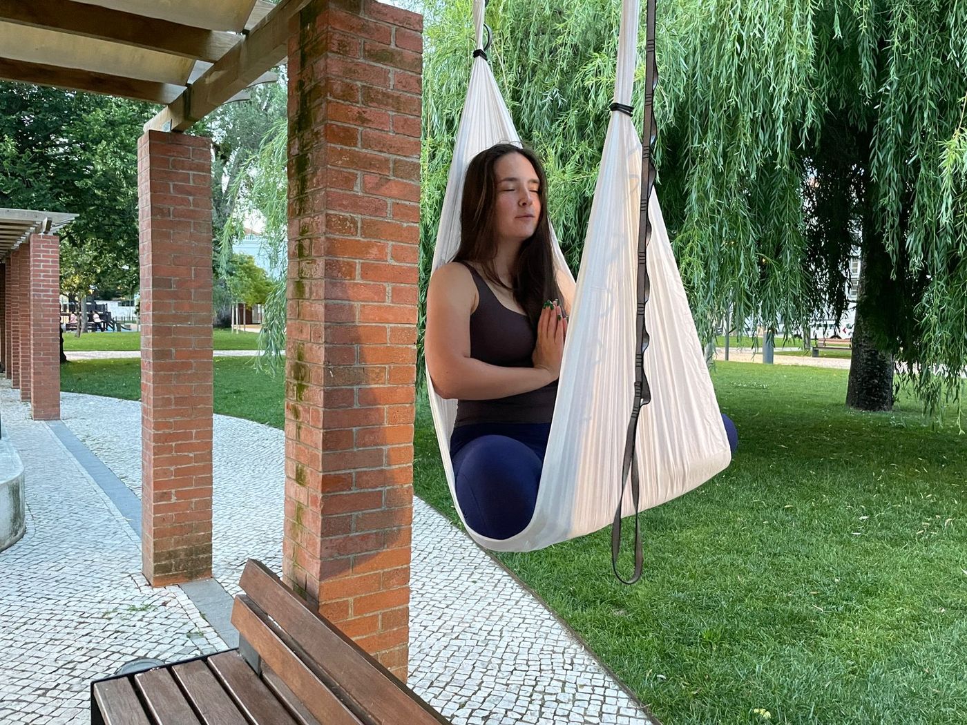 Praticante a meditar sentada num tecido branco, num jardim