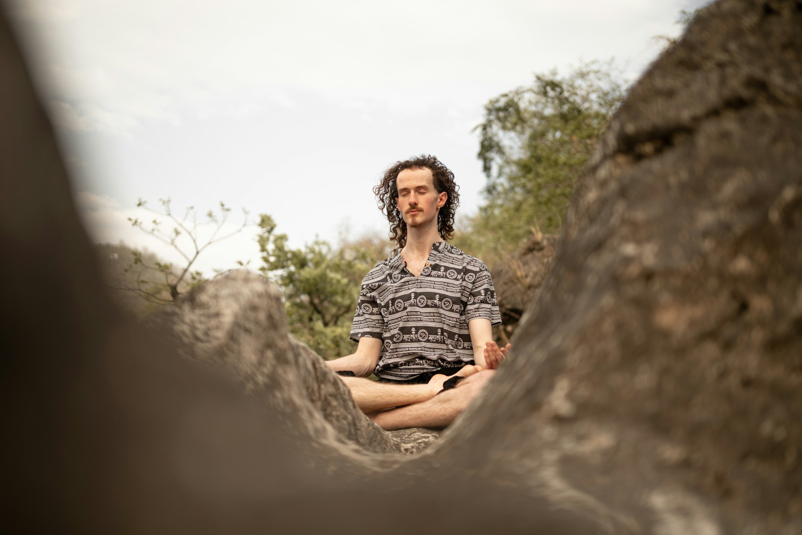 a man sitting on a rock in the middle of a forest